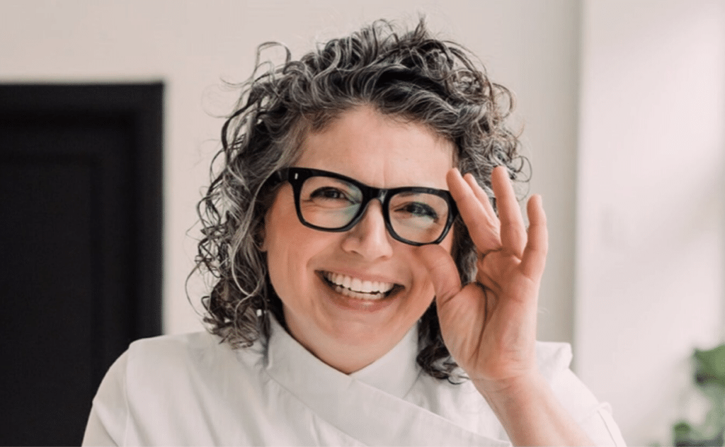 Smiling woman with large black glasses in a chef coat- Allison from Newton Of Ypsilanti