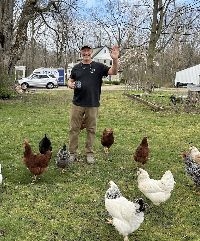 Innkeeper Tim at the Vintage inn with his chickens waving with the inn in the background