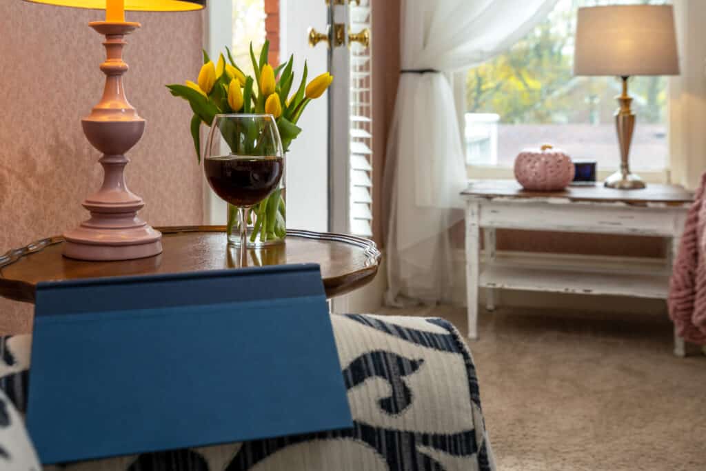 Glass of red wine on a table with a blue book on an arm chair in St. Johns