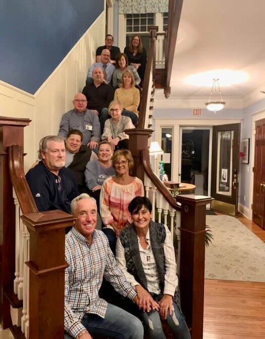 Dennis and Kim Torrey and their 12 guests sit on stairway at Nordic Pineapple B&B