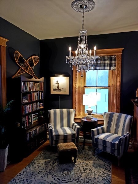 Crystal chandelier hangs over two striped chairs in a guest room at Big Bay Point Lighthouse B&B.