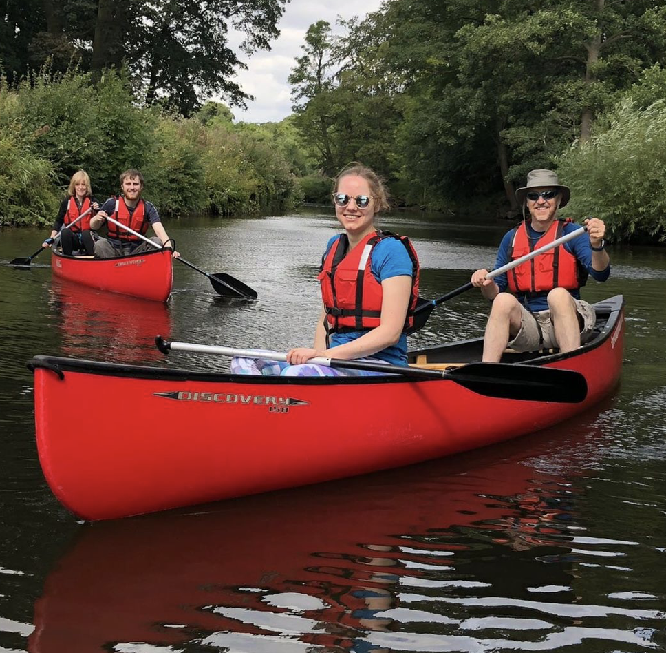 two couples canoeing the Au Sable River in red canoes