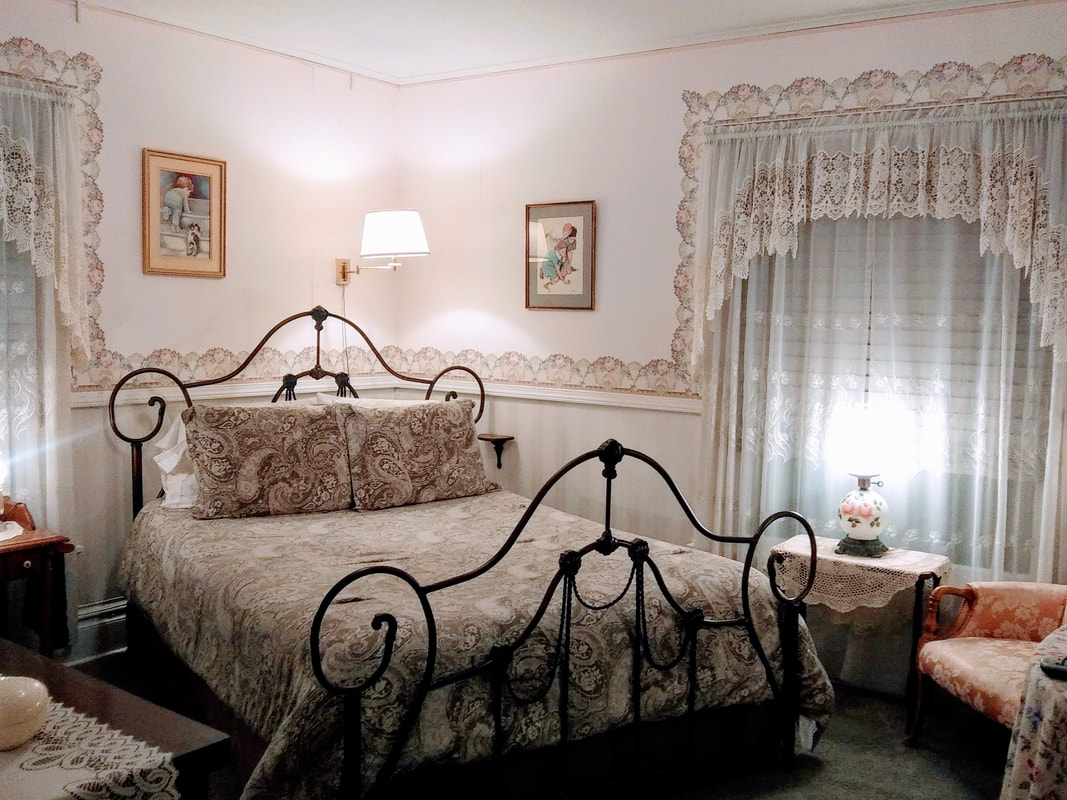 Guest room at Candlelite B&B wiht brass bed and wall lamp behind