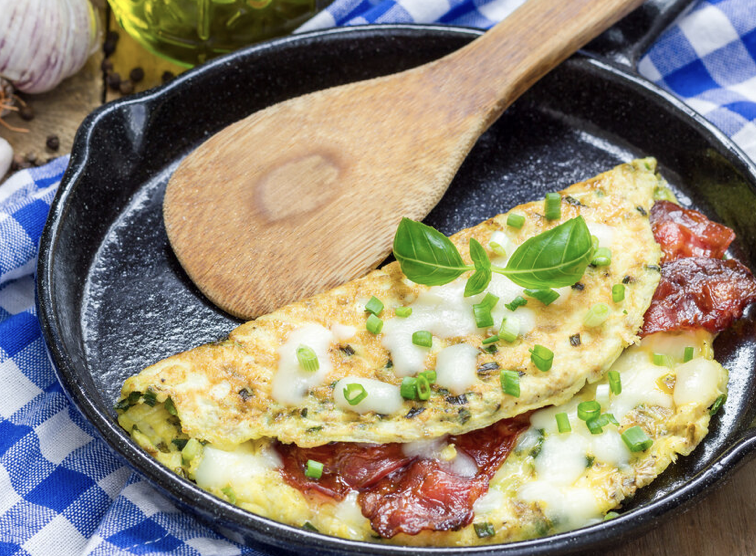 Bacon and cheese omelet in a black skillet with a wooden spoon from the Canfield House in Onekama