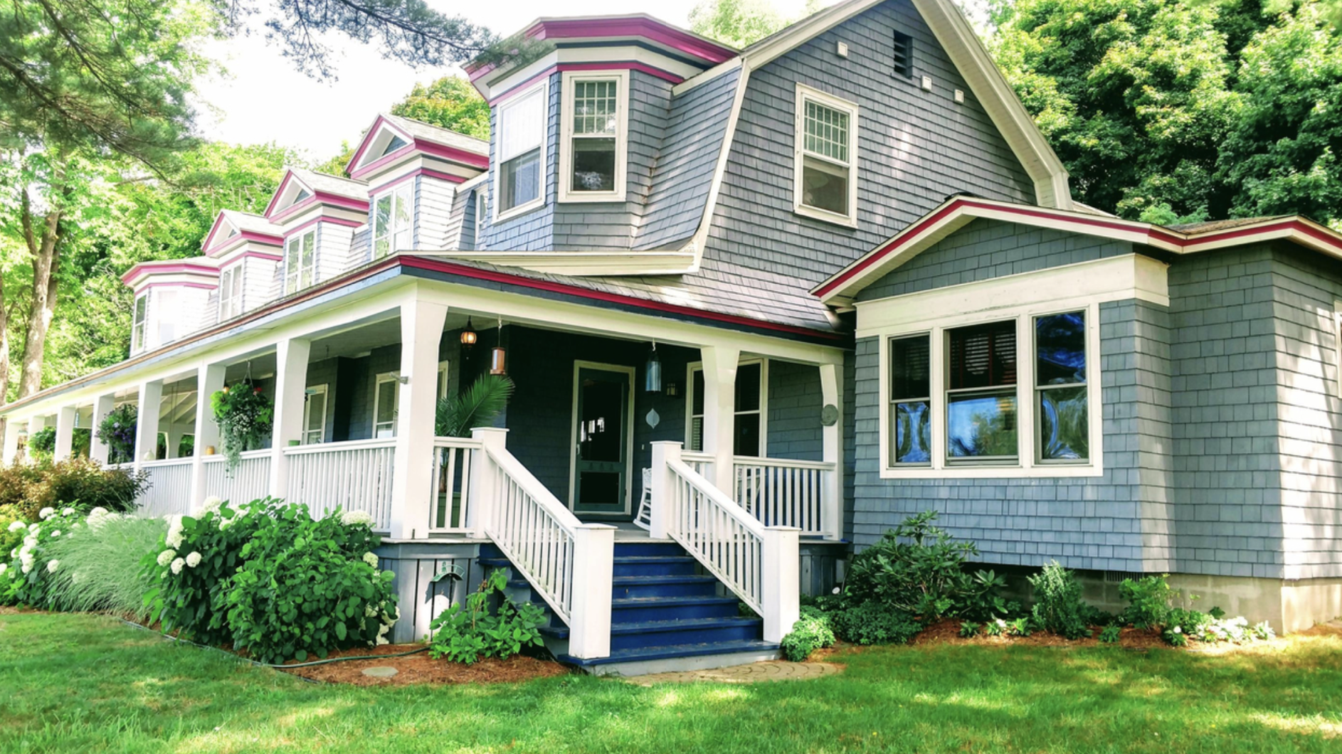 Side view of the Canfield House with Porch-grey shingled building with white trim in the town of Onekama