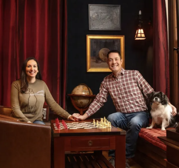 Young couple holding hands over a chess board with a dog watching