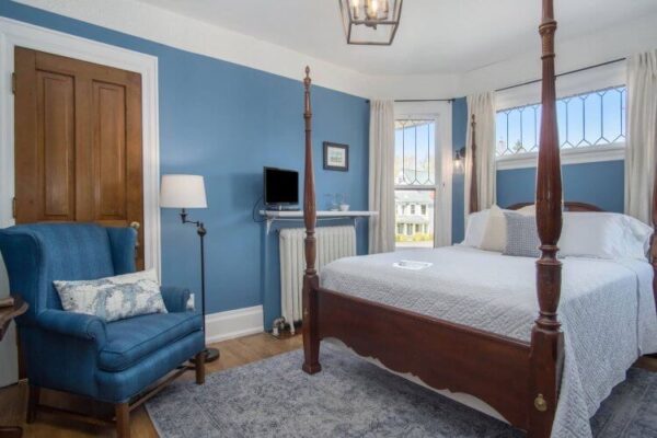 Guest room with blue walls and white spread at the Lamplighter B&B