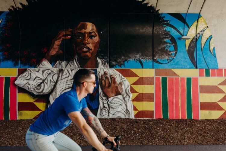 Bicyclist rides past a colorful mural 