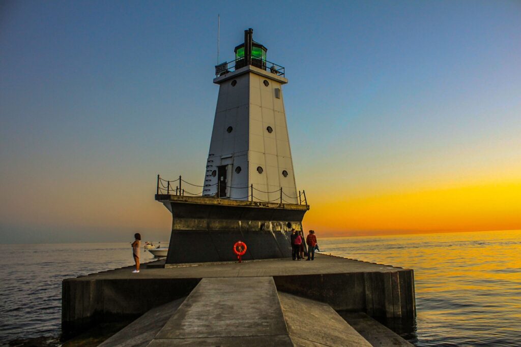 Ludington's North Breakwater Lighthouse at sunset with people walking on the pier