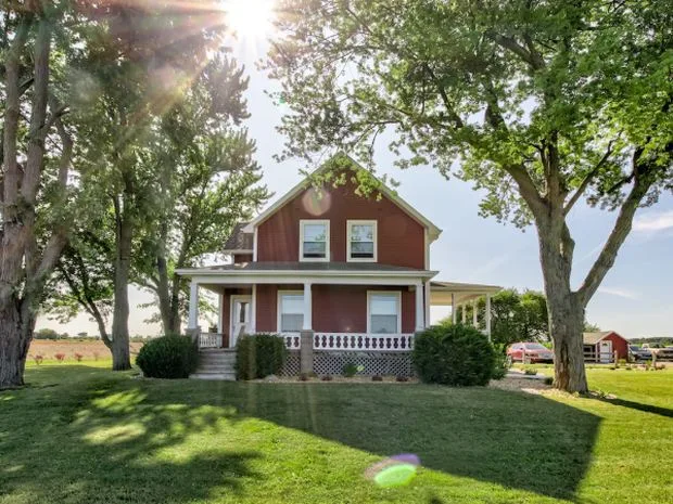 Red Farmhouse with green lawn and trees at the Frankenmuth Country B&B