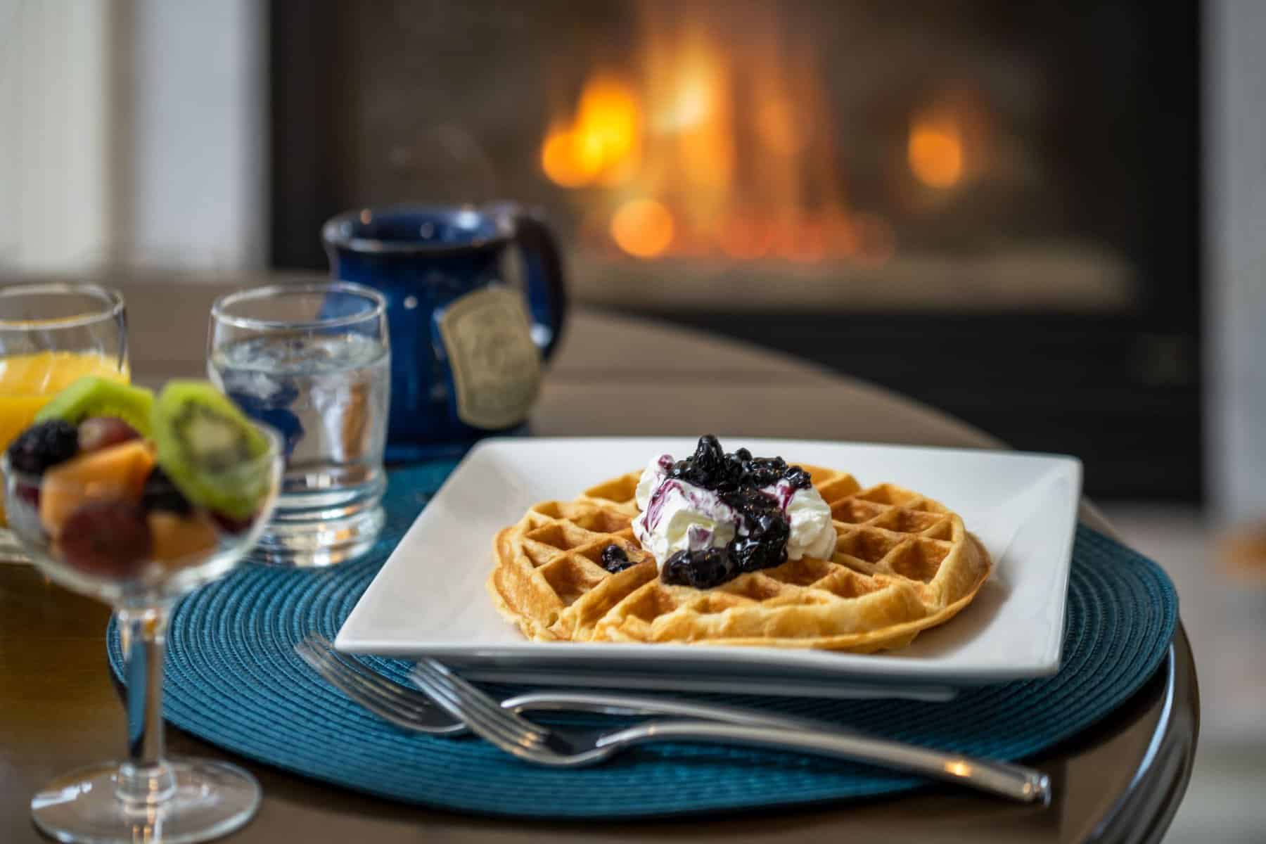 Breakfast setting at House on the Hill Bed and Breakfast, waffle, fruit, coffee and fireplace