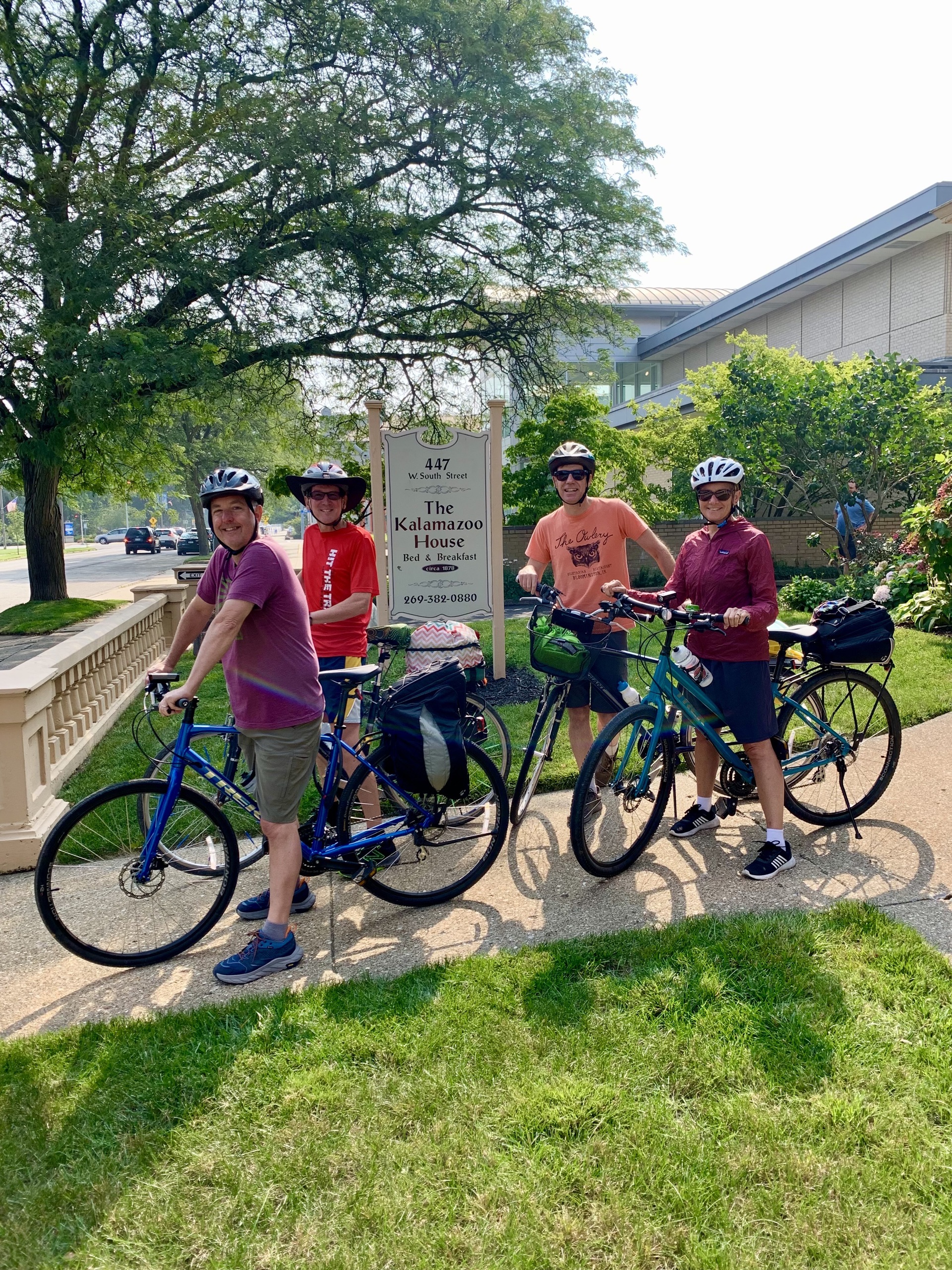 Four bicyclists stand in front of Kalamazoo House