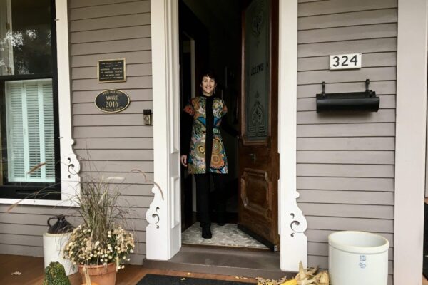 Innkeeper greeting guests at the front door in the fall