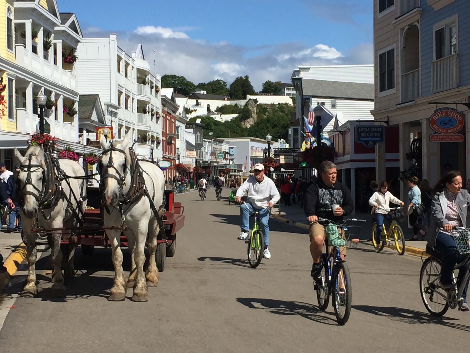 Horse-drawn wagon and bicycles share the Michigan bike trail on Mackinac Island