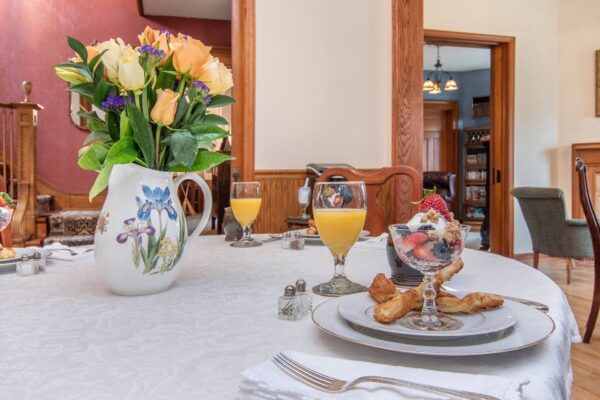 Formal breakfast table at the Lamplighter that includes roses, fruit cup with orange juice