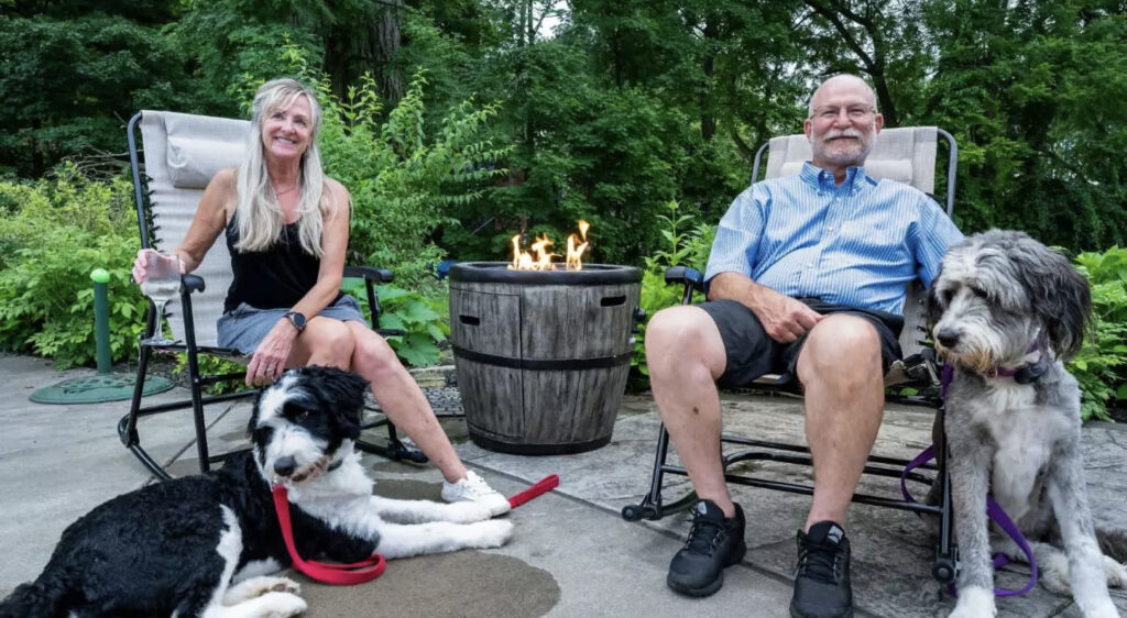 Two innkeepers sitting beside a fire pit with their two dog