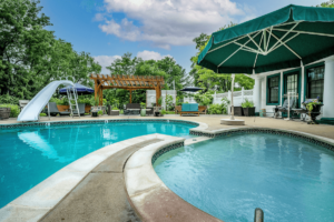 Outdoor pool with green umbrella and veranda