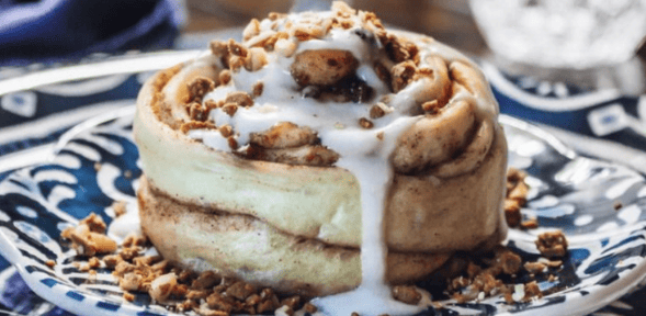 Cinnamon Roll with dripping glaze on a blue plate