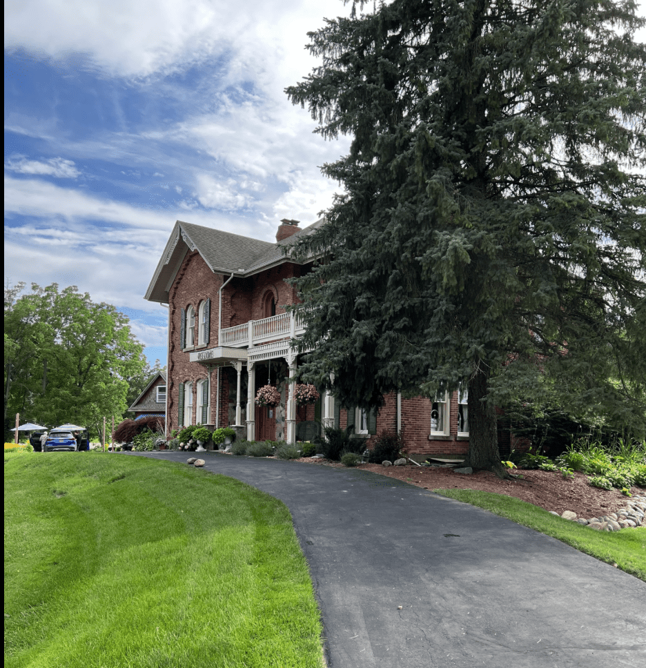 Red brick building with a green lawn and large fir tree