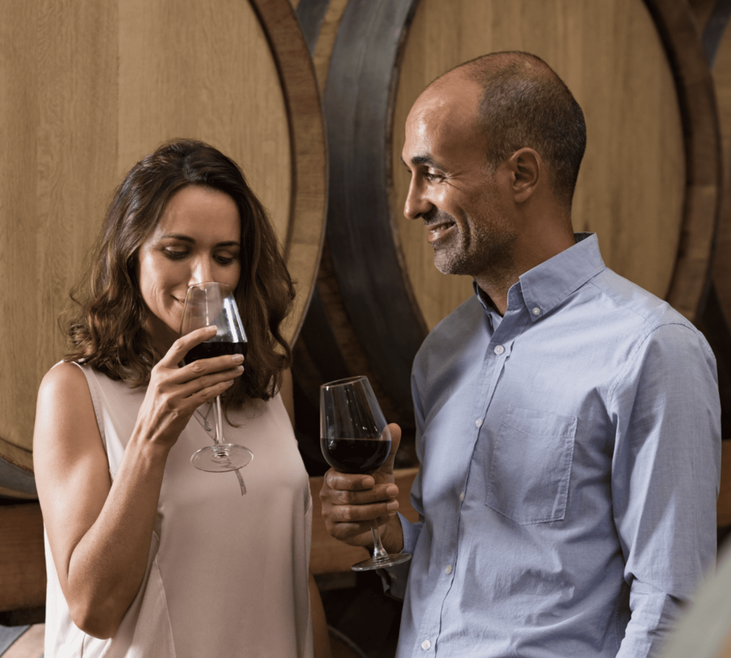 Couple tasting wine with a wine barrel behind themLake Michigan Shore Wine Trail