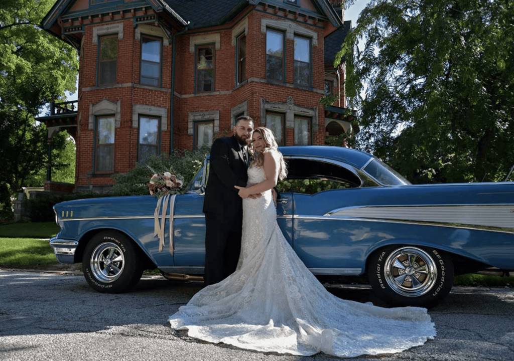 Bride and groom standing in front of a old historic car