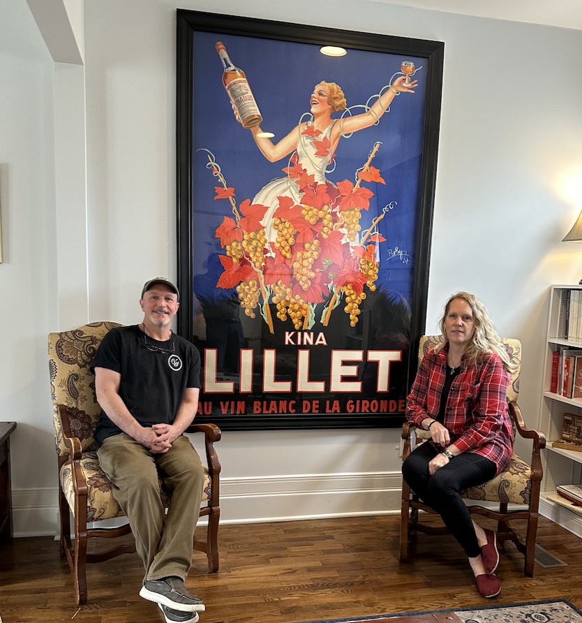 Vintage Inn hosts sitting in front of a modern poster