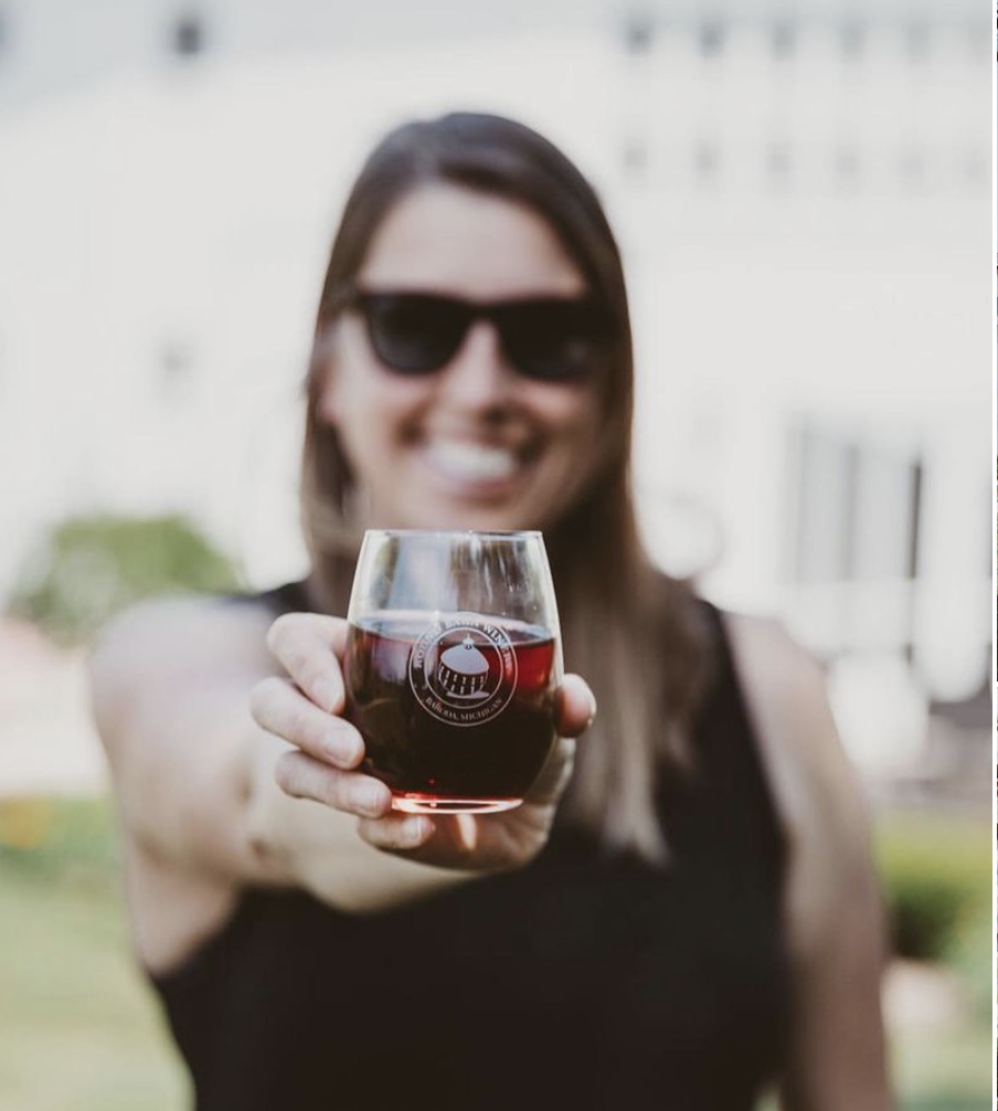 Young woman with sunglasses holding a glass of red wine in front of her