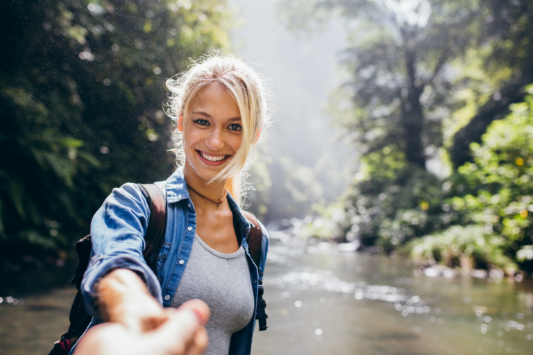 Woman hiking near a river getting a hands up