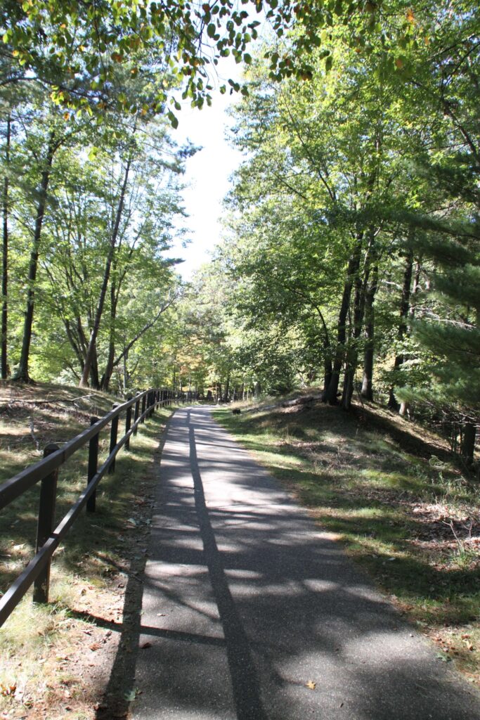 Walk trail in Ludington, Michigan that is paved for bikers and a side wooden fence.