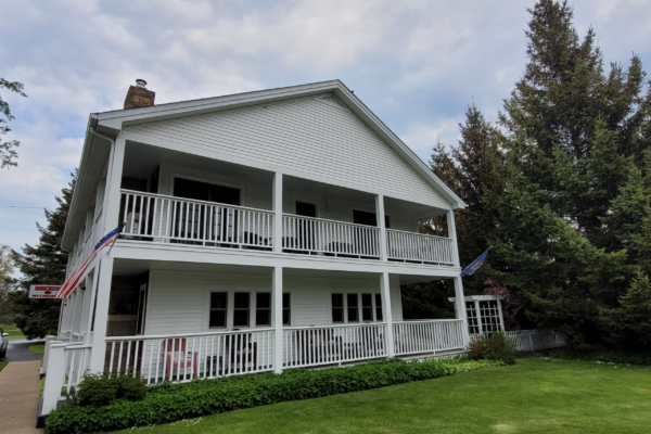 White two-story building with a porch on both floors