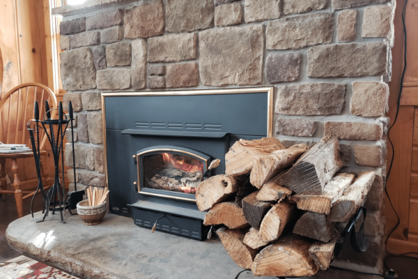 Stone fireplace with a stack of wood beside at Borchers Au Sable