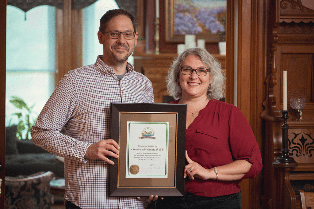 Couple standing with a #MichBnB Certificate