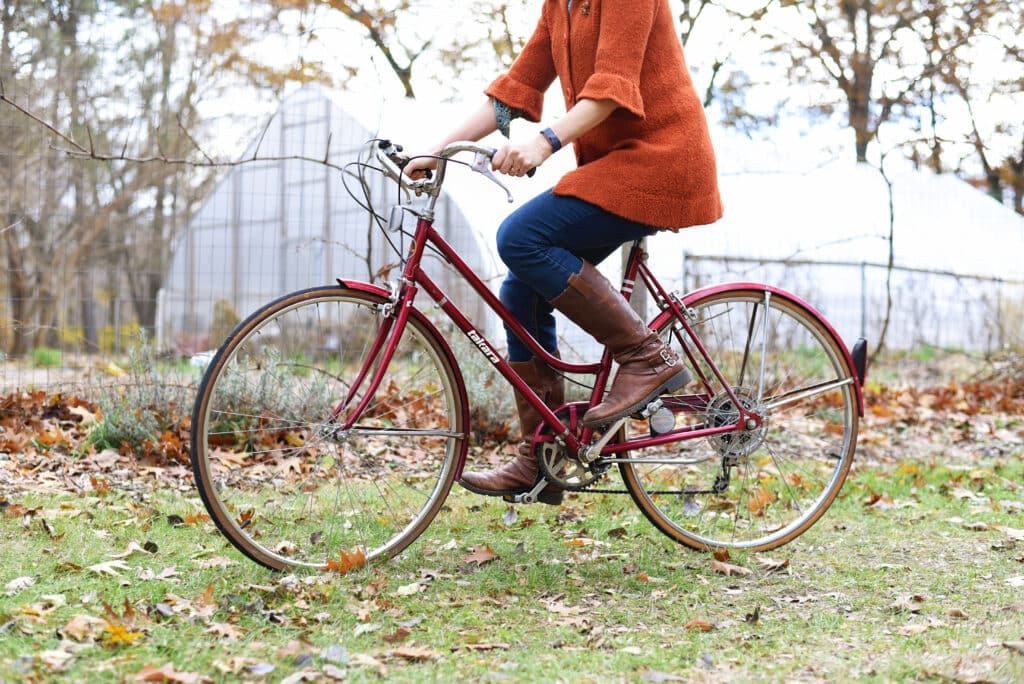 Woman wearing a orange sweater riding a bike at Goldberry Woods