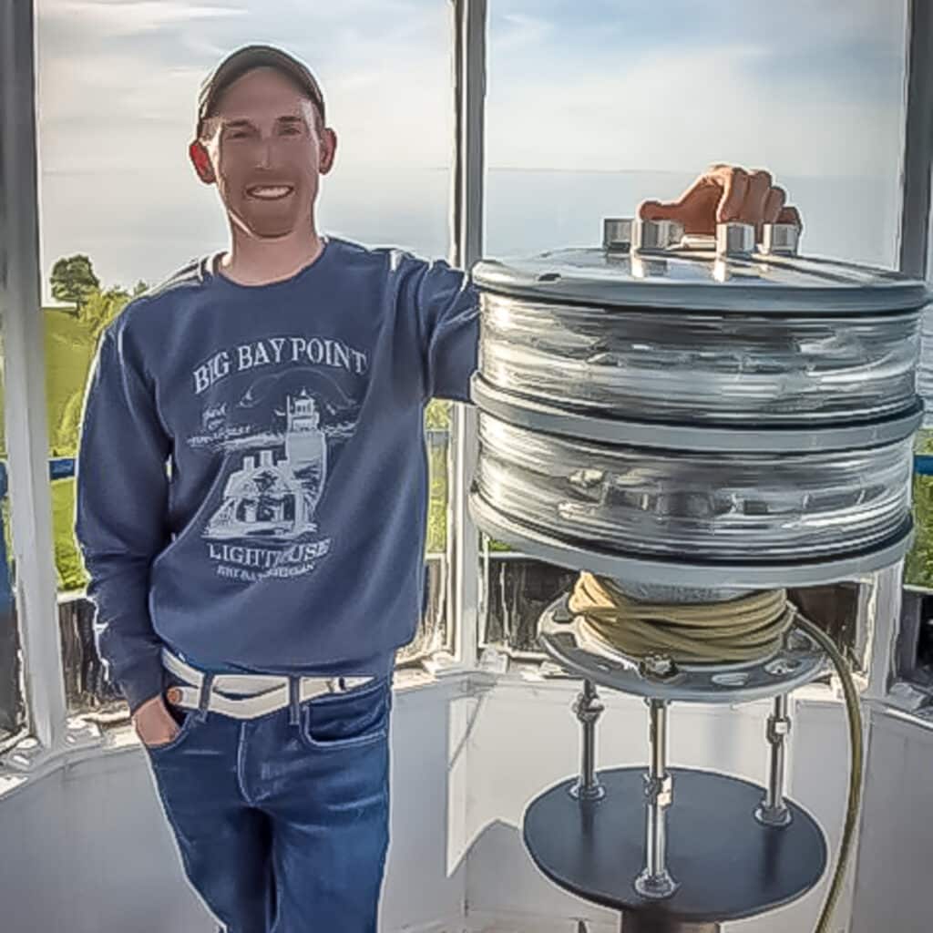 Nick leaning against the lighthouse lens at the Big Bay Lighthouse