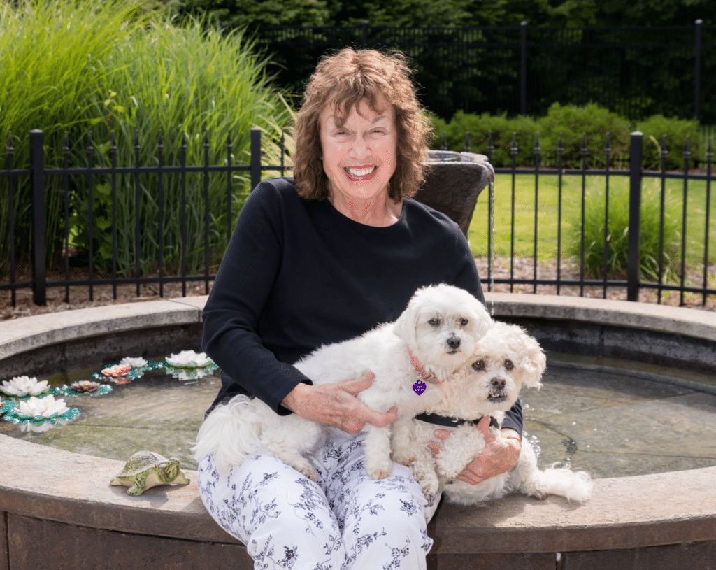 Innkeeper sitting by the fountain with two dogs at the Inn at Old Orchard Road