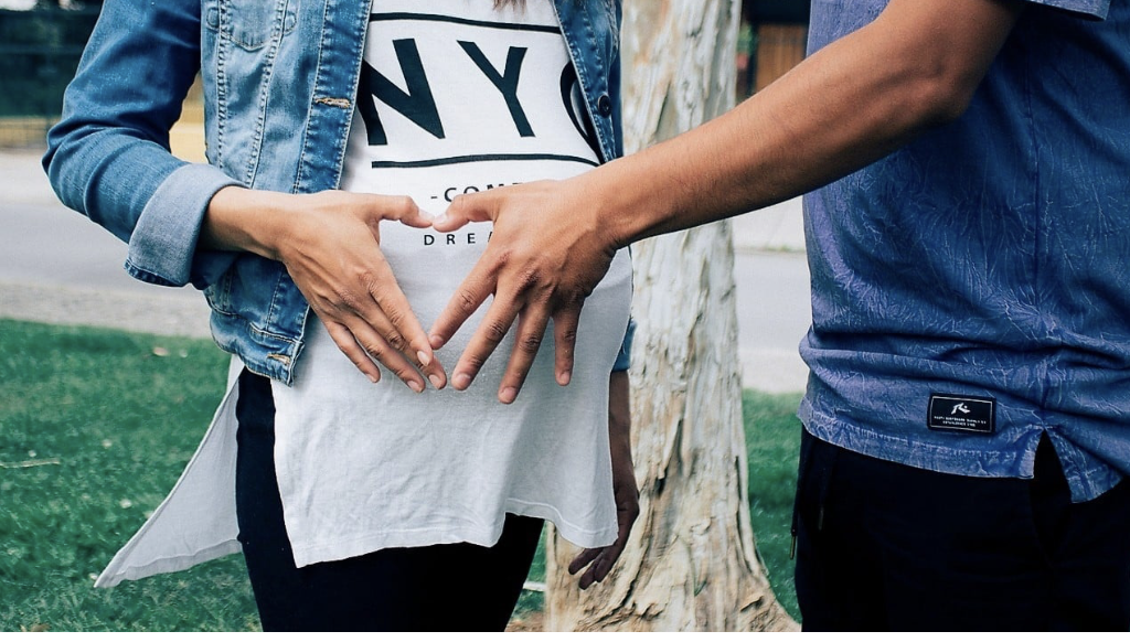 Pregnant mom with partner's hand on her belly