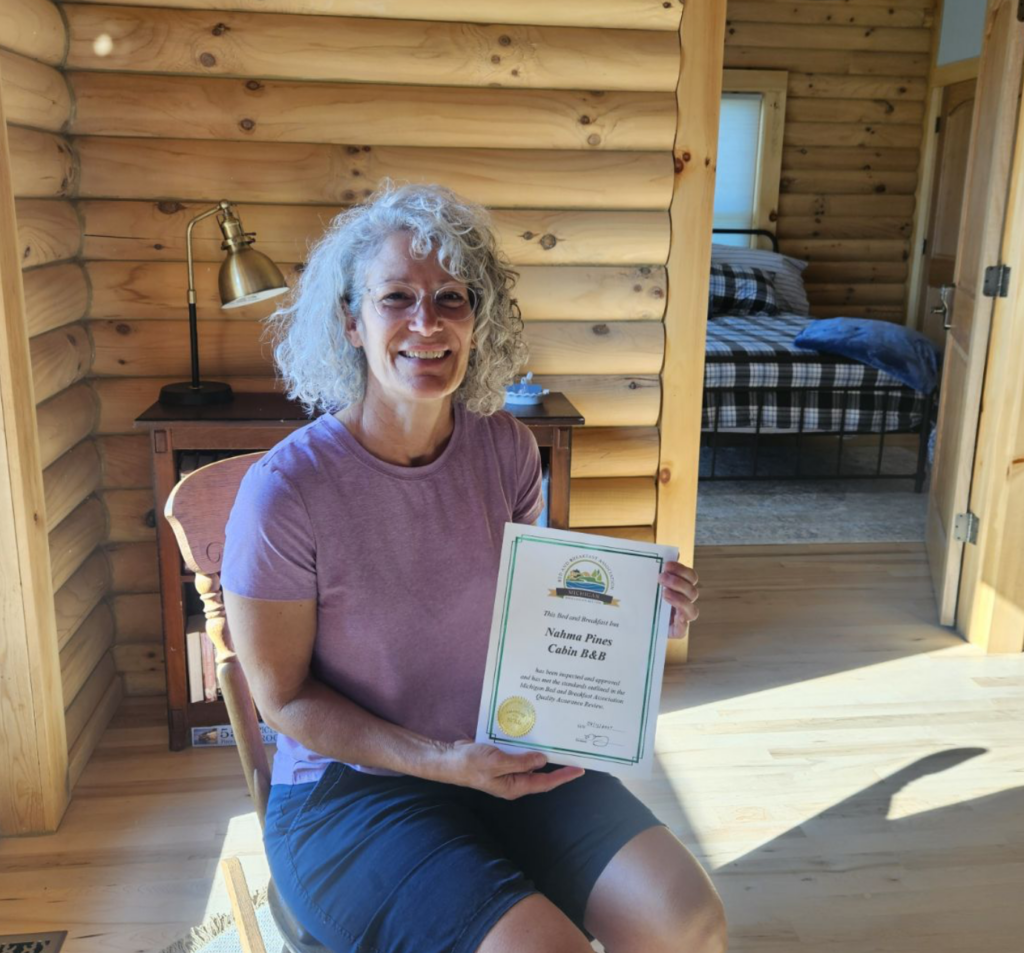 Amy from Nahma Pines holding her MichBnB certificate