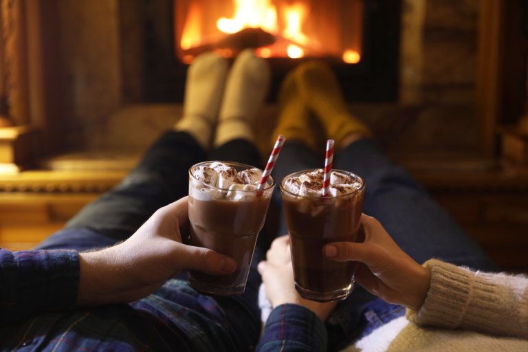 Couple in front of a fire with winter socks and hot chocolate