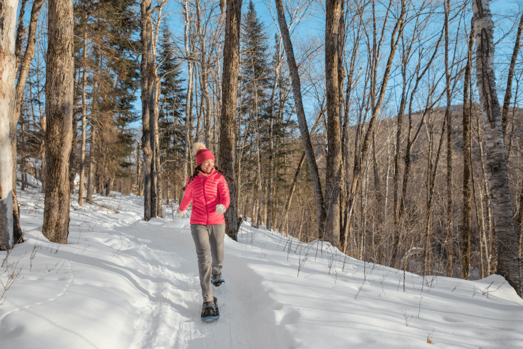 Girl in a red jacket snow-shoeing in winter